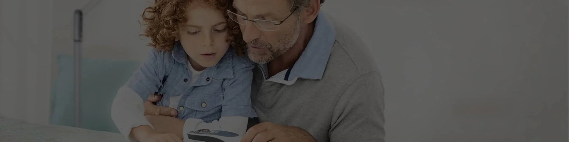 Père et enfant lisant avec une loupe electronique