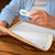 Personne âgée lisant un journal à l’aide d’une loupe de lecture blanche avec lumière LED, assise à une table en bois.
