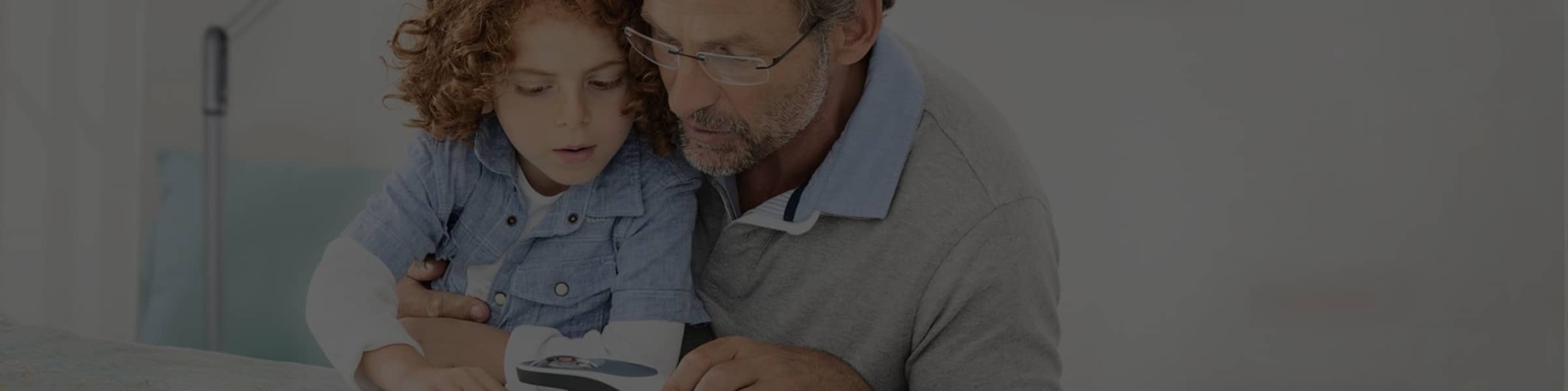 Père et enfant lisant avec une loupe electronique