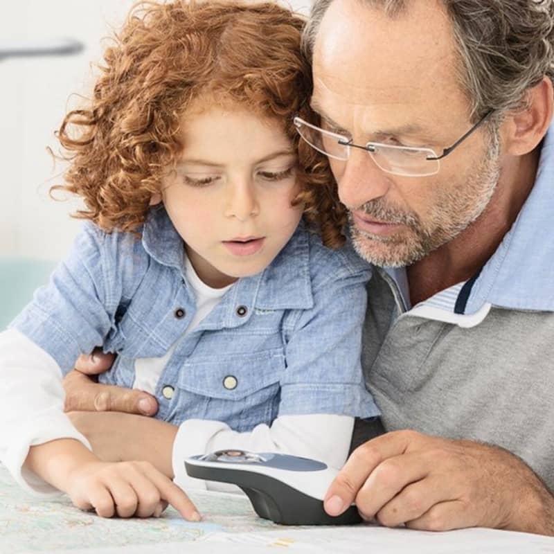 Un père et son enfant malvoyant utilisant une loupe electronique